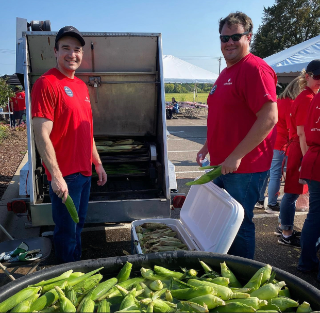 Image of employees loading corn on the cob into roaster